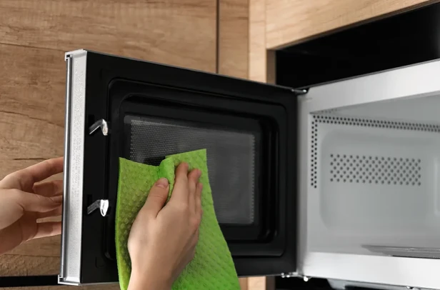 Person cleaning microwave with a lemon and vinegar solution
